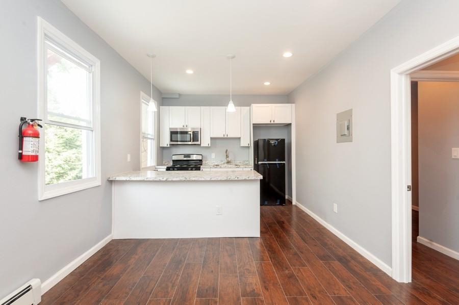 705 8th Street, Unit 2 Union City, NJ 07087 - Photo 5 of 19 a kitchen with stainless steel appliances granite countertop a refrigerator a sink dishwasher a stove and white countertops with wooden floor