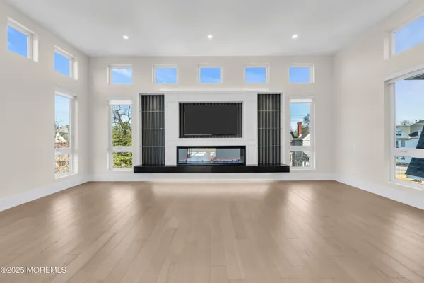 an empty room with wooden floor fireplace and windows