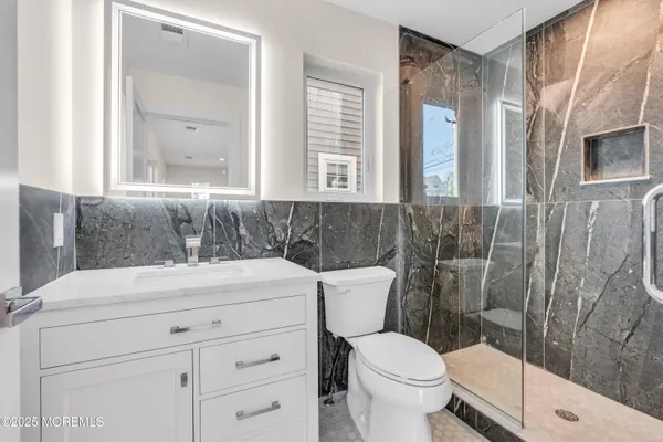 a bathroom with a sink a toilet a mirror and a shower