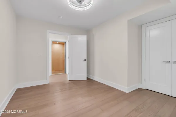 a view of an empty room with wooden floor and closet