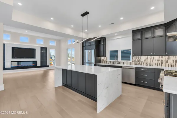 a large kitchen with stainless steel appliances a large counter top a stove and a sink