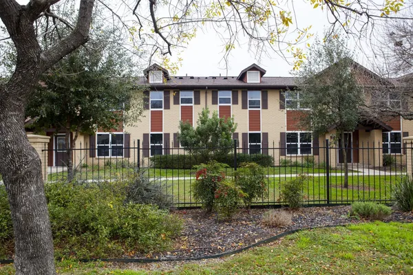 a front view of a house with a garden and trees