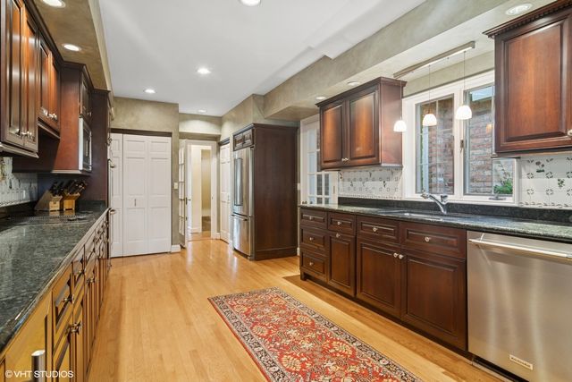 a large kitchen with stainless steel appliances granite countertop a refrigerator a sink dishwasher a stove and white countertops with wooden floor