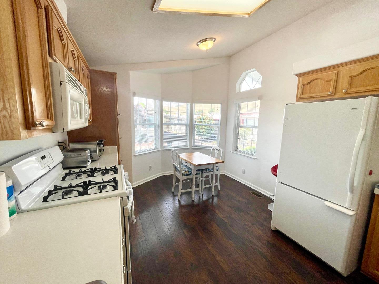 711 Old Canyon Road, Unit 13 Fremont, CA 94536 - Photo 9 of 26 a kitchen with a refrigerator a stove and a dining table with wooden floor