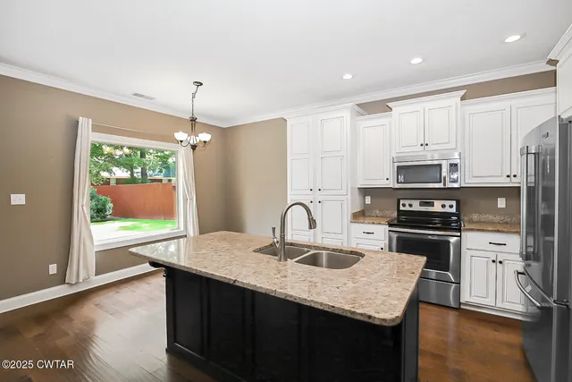 a kitchen with kitchen island granite countertop a stove top oven a sink with wooden floor and cabinets