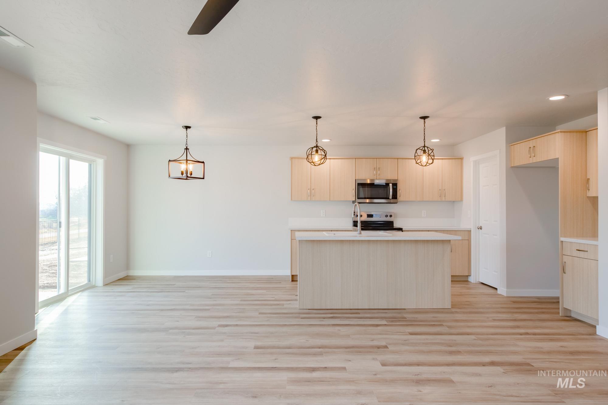 2462 West Fallon Loop Nampa, ID 83651 - Photo 12 of 23 Kitchen with light countertops, a chandelier, a kitchen island with sink, light wood-type flooring, and recessed lighting