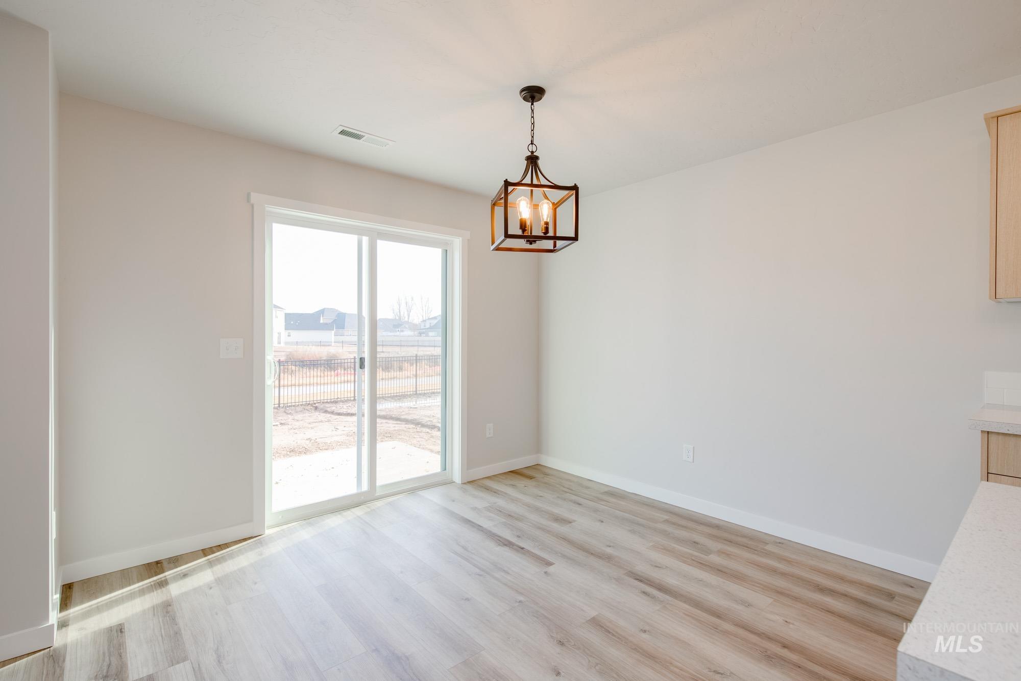 2462 West Fallon Loop Nampa, ID 83651 - Photo 6 of 23 Unfurnished dining area featuring light wood-style floors and a chandelier