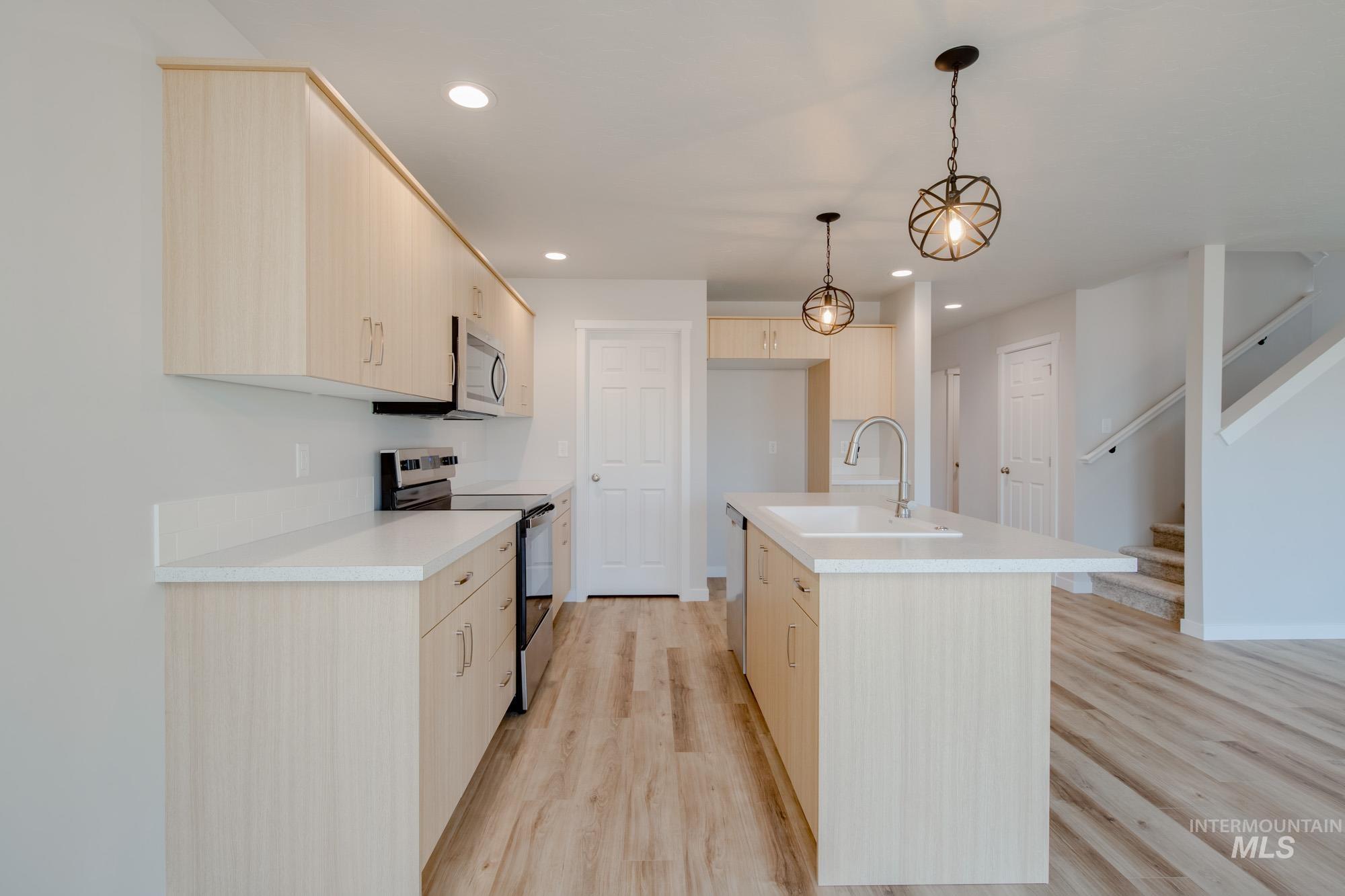 2462 West Fallon Loop Nampa, ID 83651 - Photo 7 of 23 Kitchen with appliances with stainless steel finishes, light countertops, an island with sink, decorative light fixtures, and recessed lighting