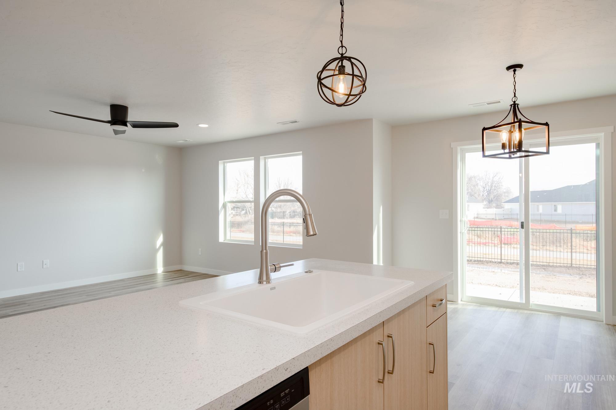 2462 West Fallon Loop Nampa, ID 83651 - Photo 22 of 23 Kitchen featuring light brown cabinets, light wood finished floors, decorative light fixtures, open floor plan, and light stone countertops