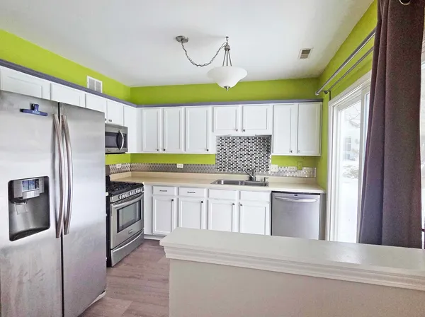 a kitchen with granite countertop white cabinets and stainless steel appliances