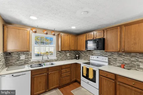 a kitchen with stainless steel appliances granite countertop a sink stove and cabinets