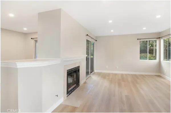 an empty room with wooden floor fireplace and windows