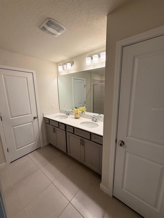 10923 Leafshore Loop Orlando, FL 32829 - Photo 21 of 44 a bathroom with a double vanity sink a mirror and a bathtub