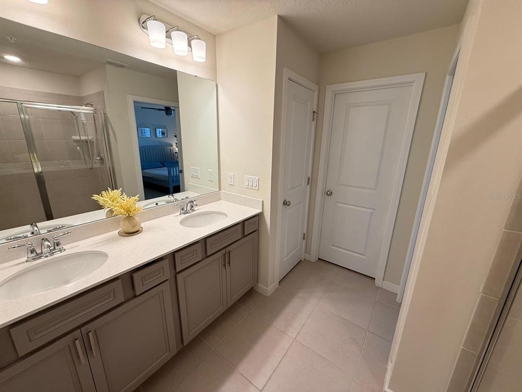 10923 Leafshore Loop Orlando, FL 32829 - Photo 23 of 44 a bathroom with a double vanity sink a mirror and a bathtub
