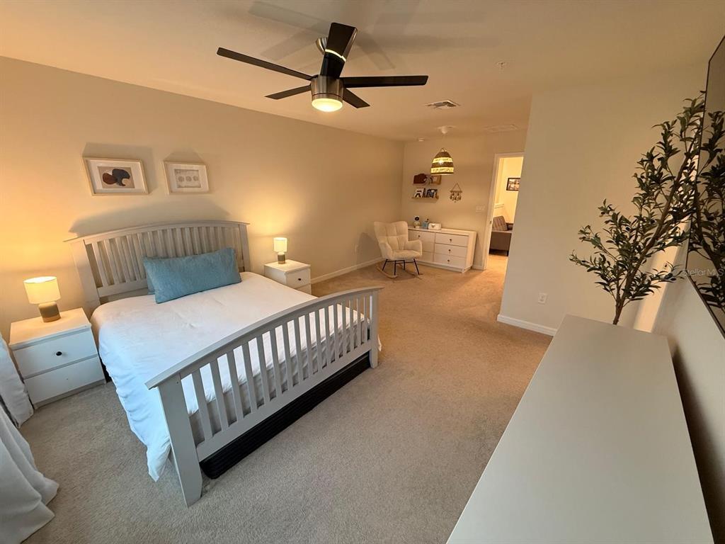10923 Leafshore Loop Orlando, FL 32829 - Photo 28 of 44 a spacious bedroom with a bed and a chandelier