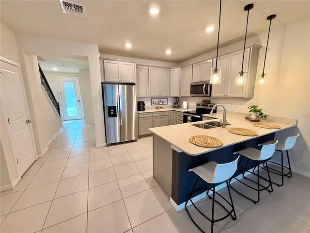 a kitchen with stainless steel appliances kitchen island granite countertop a table chairs and a refrigerator