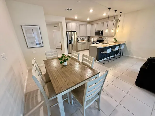 a kitchen with stainless steel appliances kitchen island granite countertop a table chairs and a refrigerator