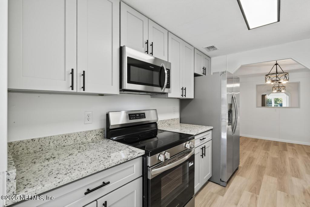 560 Quarter Horse Lane Bunnell, FL 32110 - Photo 19 of 66 a kitchen with stainless steel appliances granite countertop a stove a microwave and a refrigerator