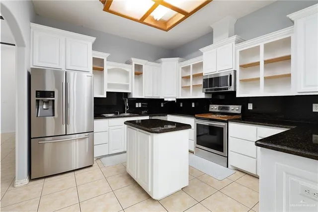 a kitchen with stainless steel appliances granite countertop a refrigerator a stove top oven and a sink with granite countertops