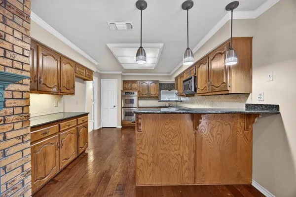 a kitchen with stainless steel appliances granite countertop a sink a stove and a wooden floors