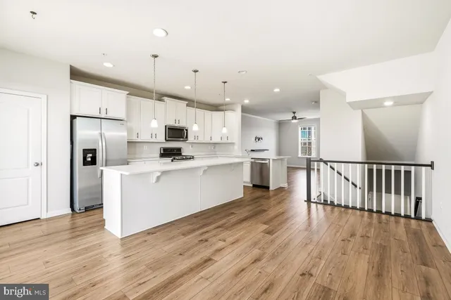 a large kitchen with a center island wooden floor stainless steel appliances and cabinets