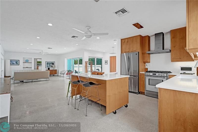 a living room with stainless steel appliances kitchen island granite countertop furniture and a refrigerator