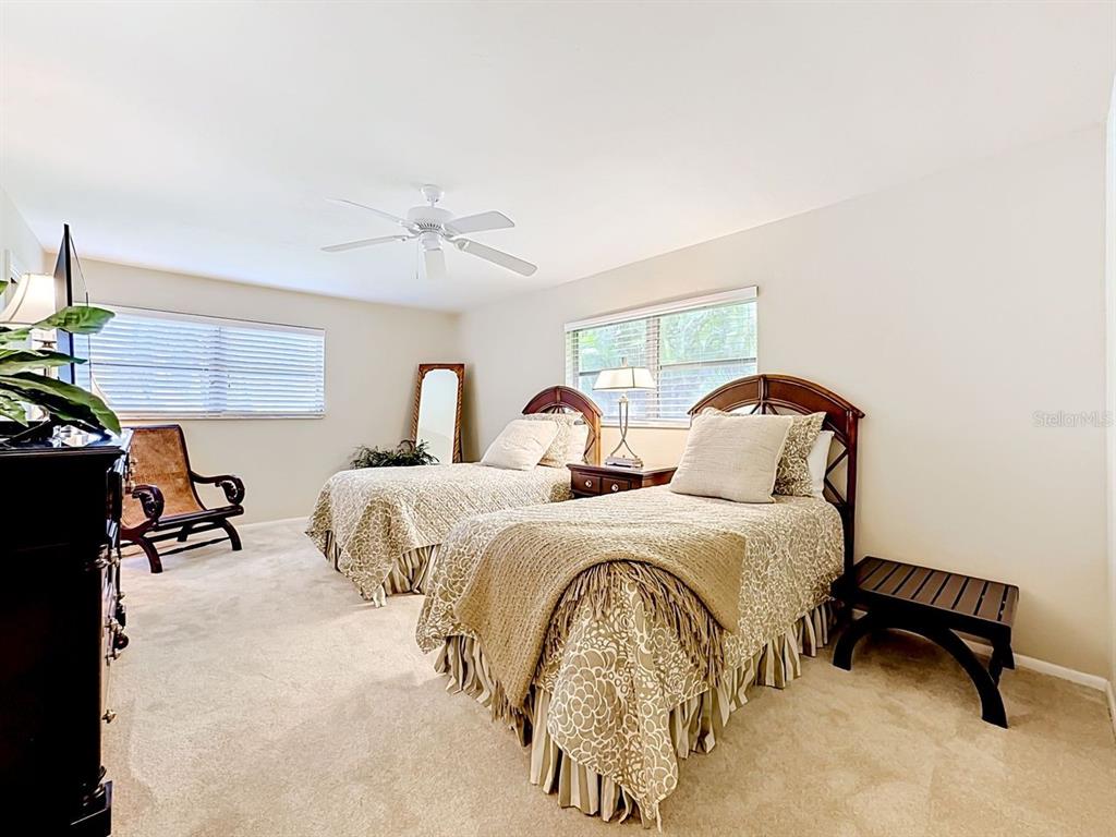 581 Yardarm Lane Longboat Key, FL 34228 - Photo 14 of 30 a spacious bedroom with two beds and a chandelier