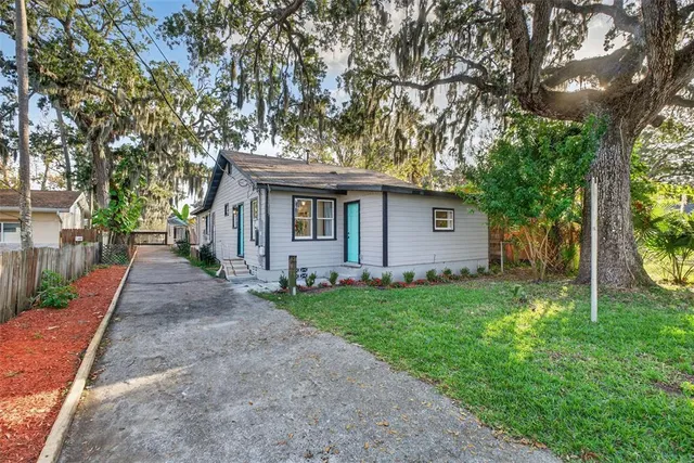 a backyard of a house with lots of plants and large trees