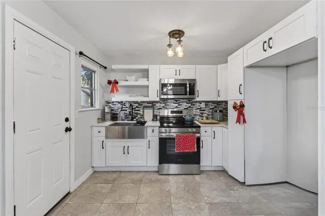 a kitchen with stainless steel appliances a sink dishwasher a stove and white cabinets with wooden floor