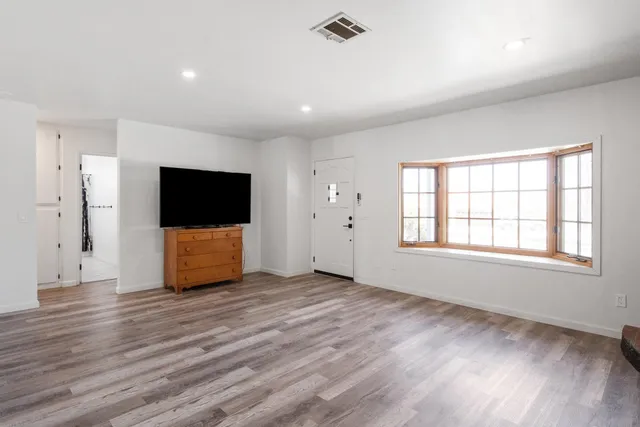 an empty room with wooden floor and windows