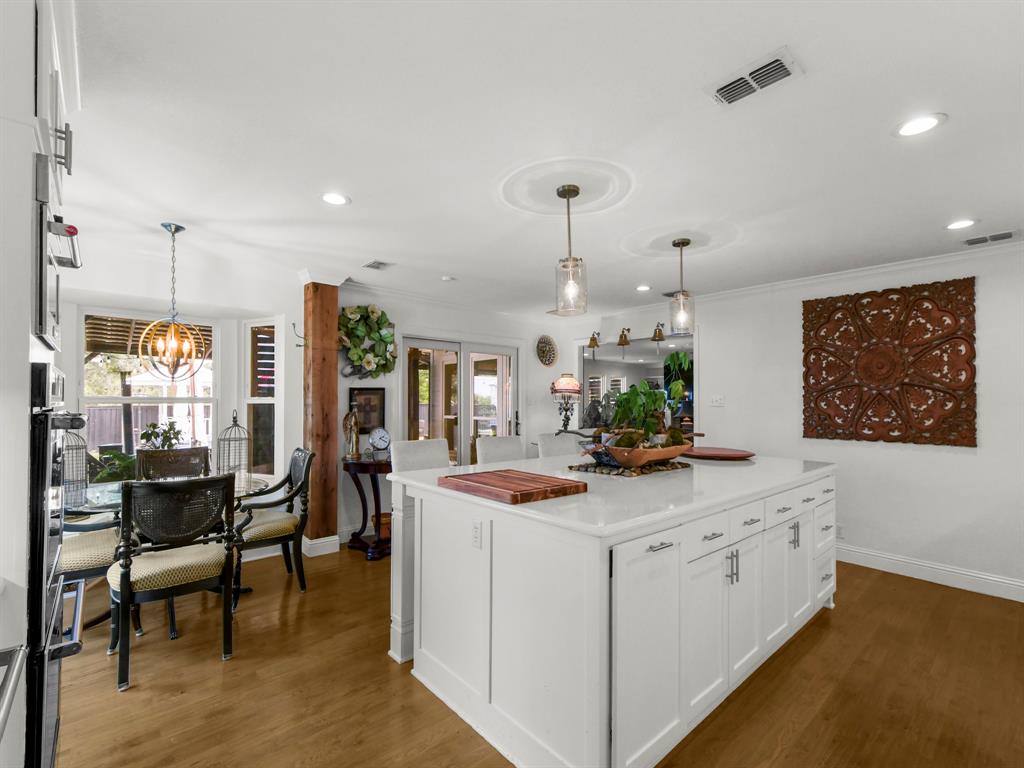 9867 Dripping Spring Road Denison, TX 75021 - Photo 14 of 40 Kitchen island with white cabinetry, a light-colored countertop, and two pendant lights