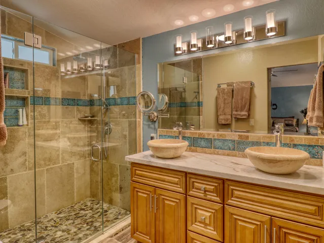 a bathroom with a granite countertop sink a mirror and shower