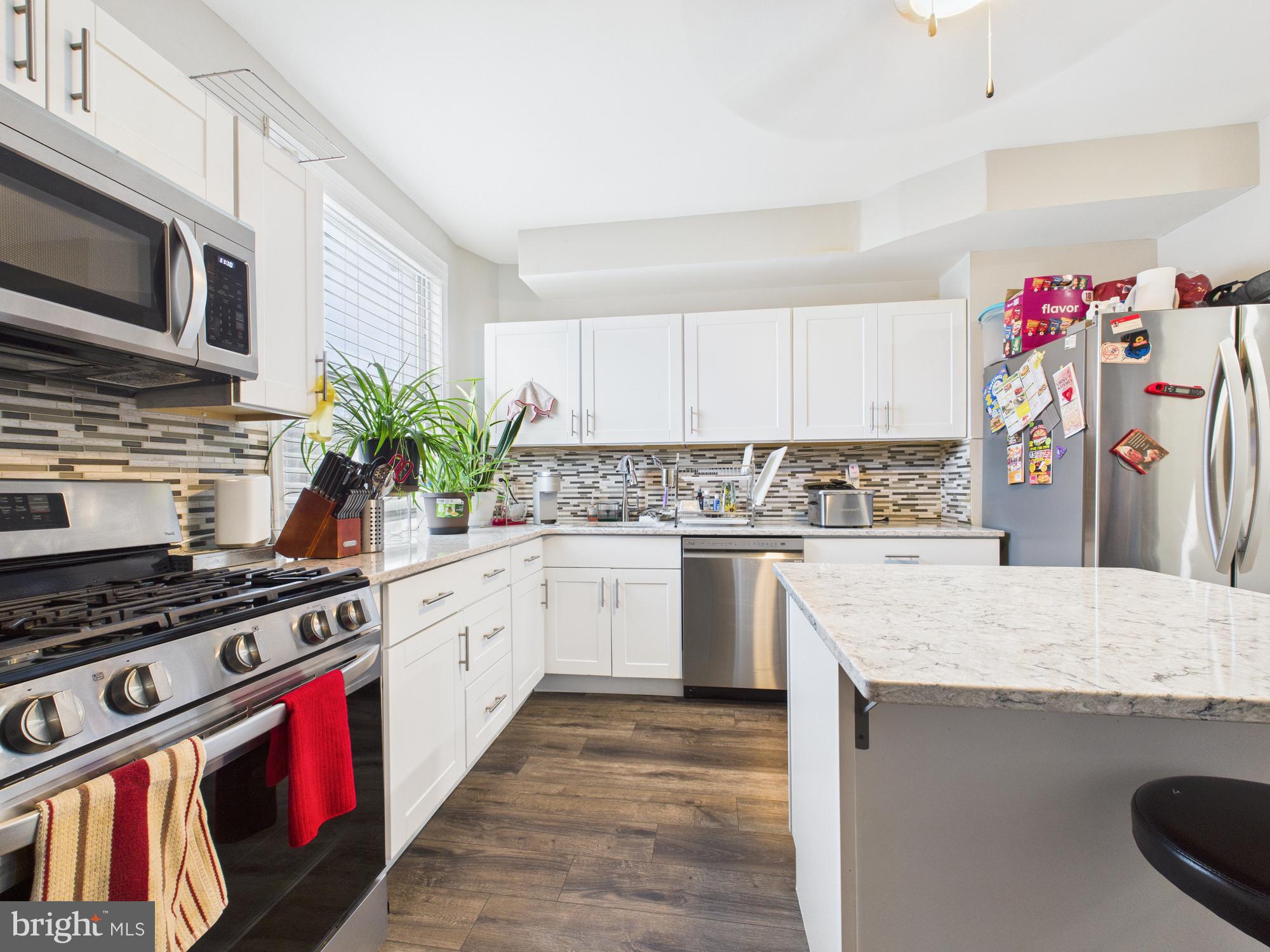 1526 North Patterson Park Avenue Baltimore, MD 21213 - Photo 16 of 31 a kitchen with kitchen island granite countertop a stove a sink dishwasher and white cabinets with wooden floor