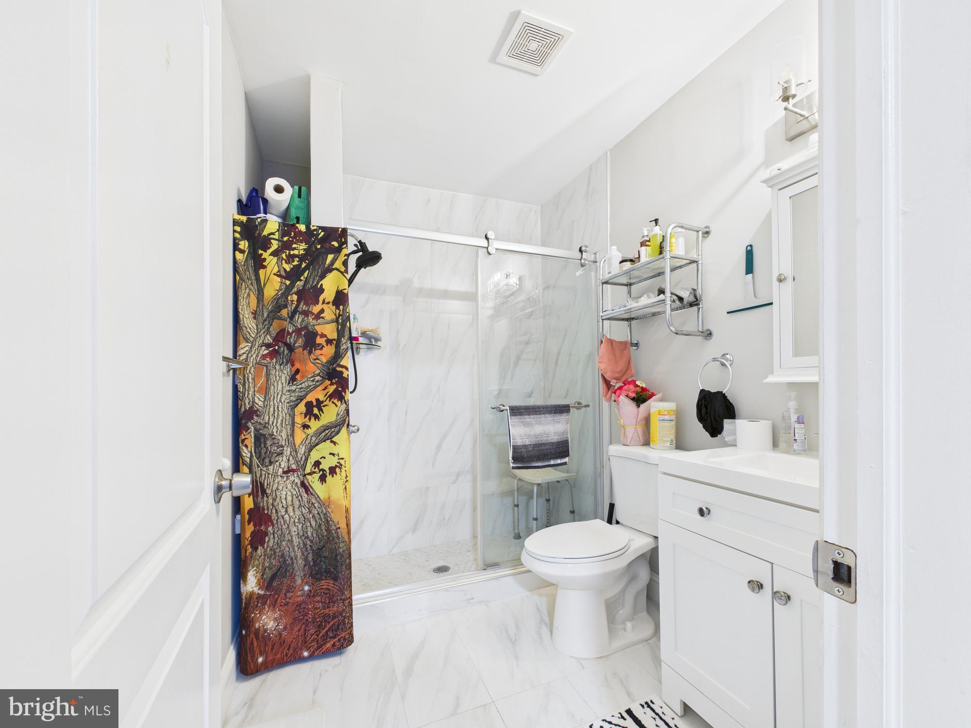 1526 North Patterson Park Avenue Baltimore, MD 21213 - Photo 17 of 31 a white toilet sitting next to a bathroom sink and a shower curtain