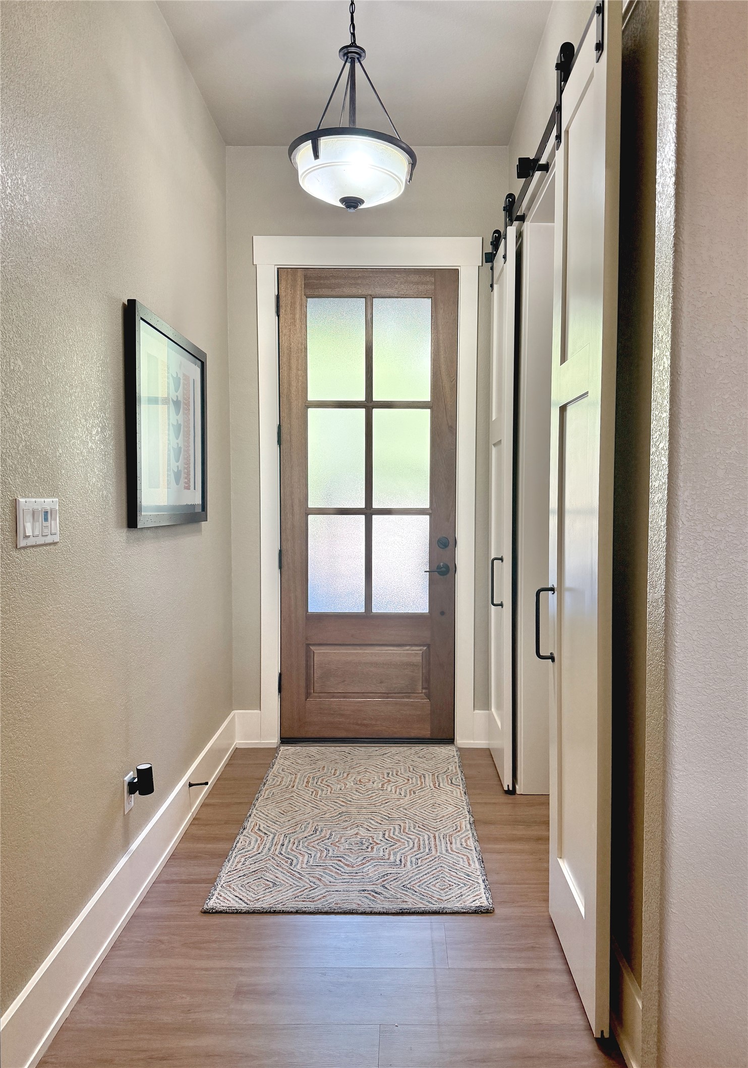 261 Barber Drive Wimberley, TX 78676 - Photo 4 of 37 Doorway to outside with a textured wall, a barn door, and wood finished floors
