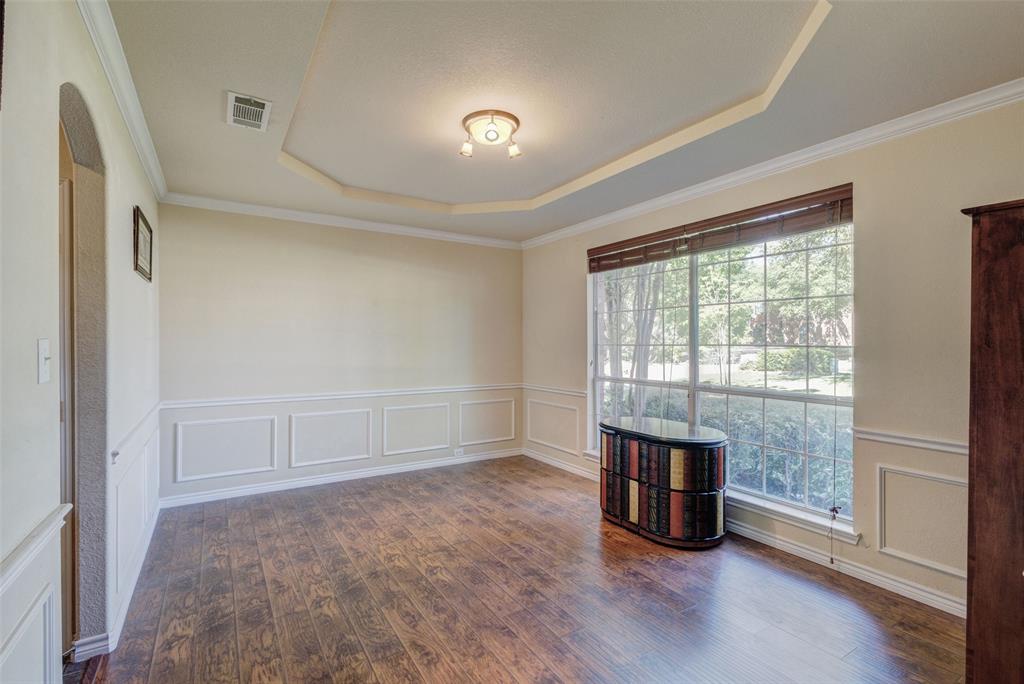 10414 Broadmoor Lane Rowlett, TX 75089 - Photo 5 of 38 Empty room with a decorative wall, a wainscoted wall, dark wood finished floors, ornamental molding, and a raised ceiling