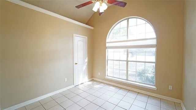 an empty room with windows and chandelier fan