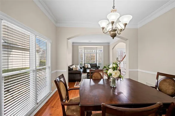 a dining room with wooden floor a chandelier a wooden table and chairs