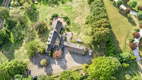 an aerial view of residential house with outdoor space and trees all around