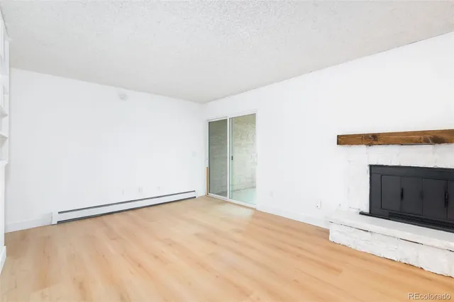 a view of an empty room with wooden floor and a fireplace