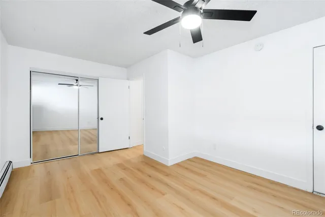 an empty room with wooden floor a ceiling fan and closet area