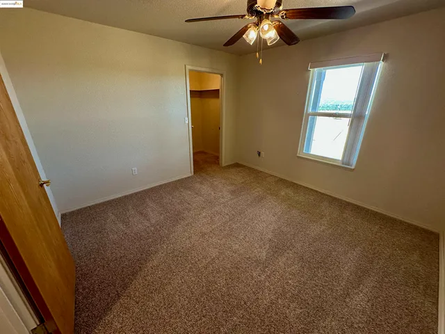 an empty room with a chandelier fan and windows