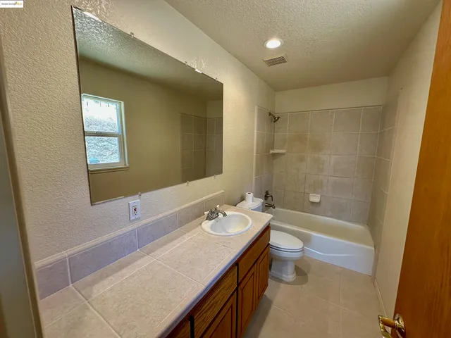 a bathroom with a granite countertop sink a toilet and shower