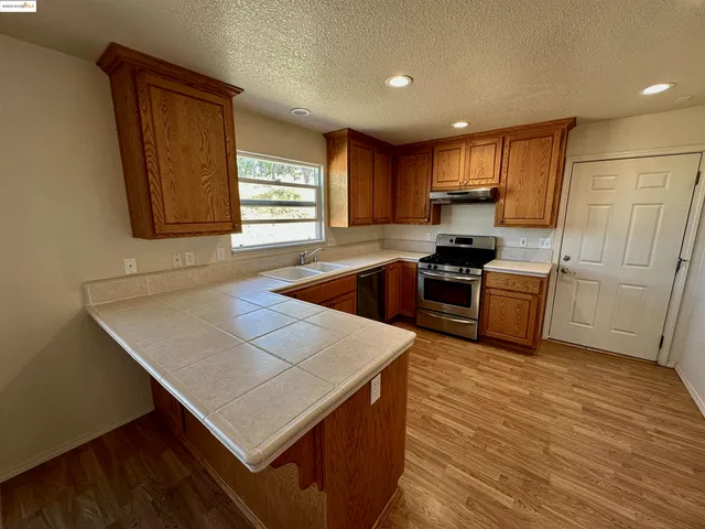 a kitchen with stainless steel appliances granite countertop a sink dishwasher stove and refrigerator with wooden floor