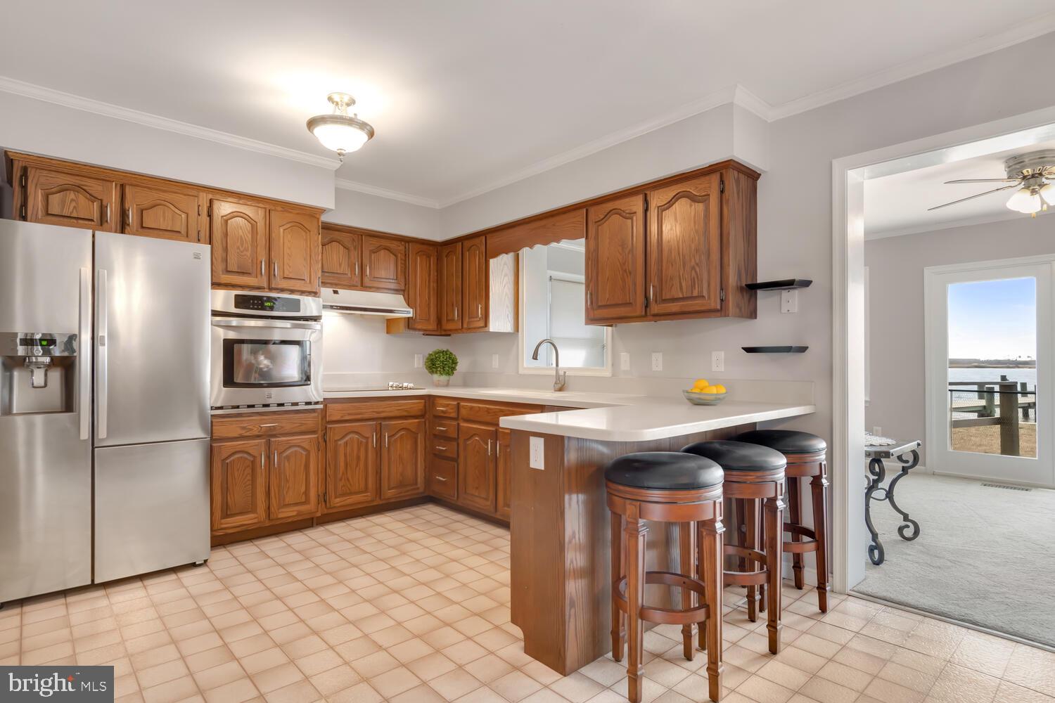 1015 Long Point Road Grasonville, MD 21638 - Photo 17 of 39 a kitchen with stainless steel appliances granite countertop a refrigerator a sink dishwasher a stove and white countertops with wooden floor