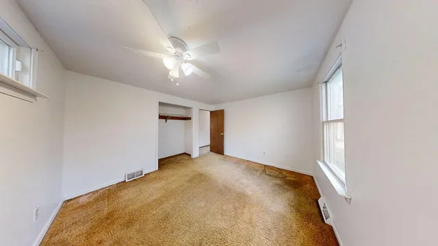 a view of a big room with windows and chandelier fan