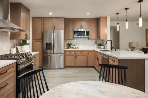 a kitchen with stainless steel appliances granite countertop a sink a stove a refrigerator cabinets and a kitchen island