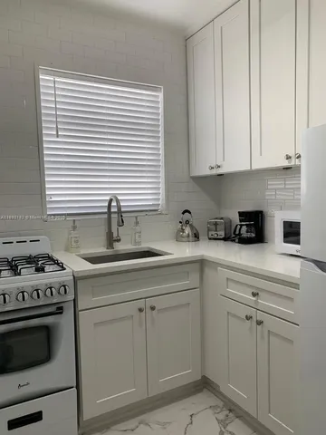 a kitchen with white cabinets and white appliances