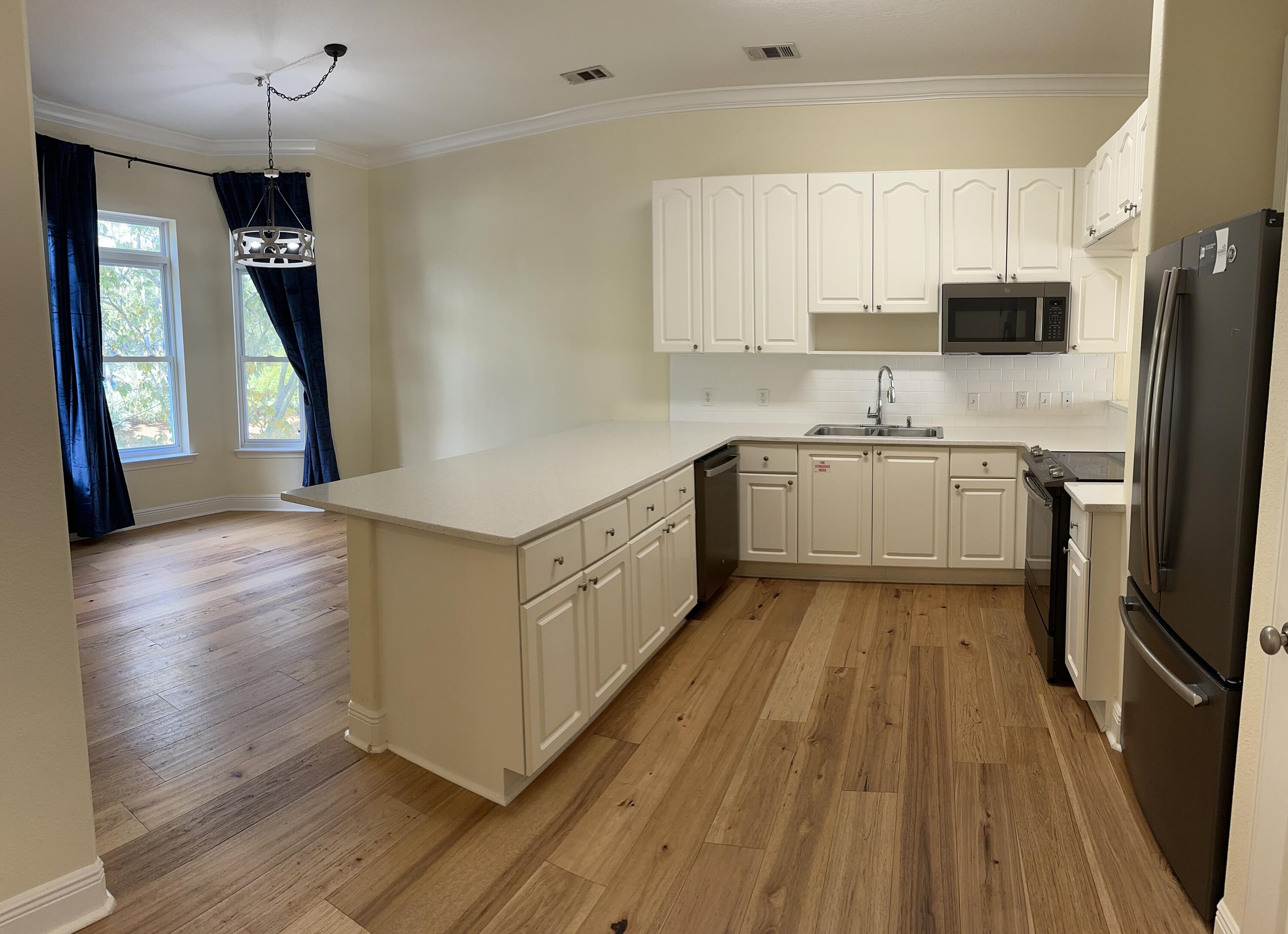 56 Spires Lane, Unit E16 Santa Rosa Beach, FL 32459 - Photo 10 of 17 a large kitchen with a white stove top oven a sink dishwasher and a refrigerator with wooden floor
