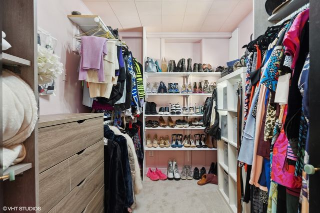 a view of walk in closet with clothes and shoes